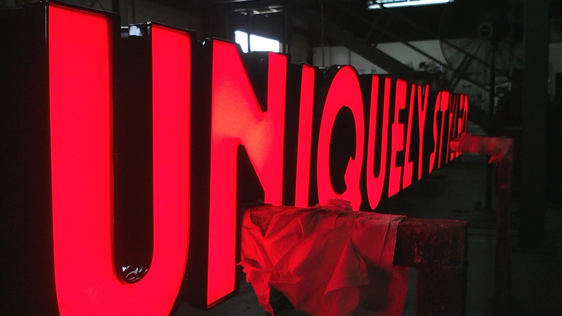 A large red sign that says `` unique '' is lit up in a dark room.