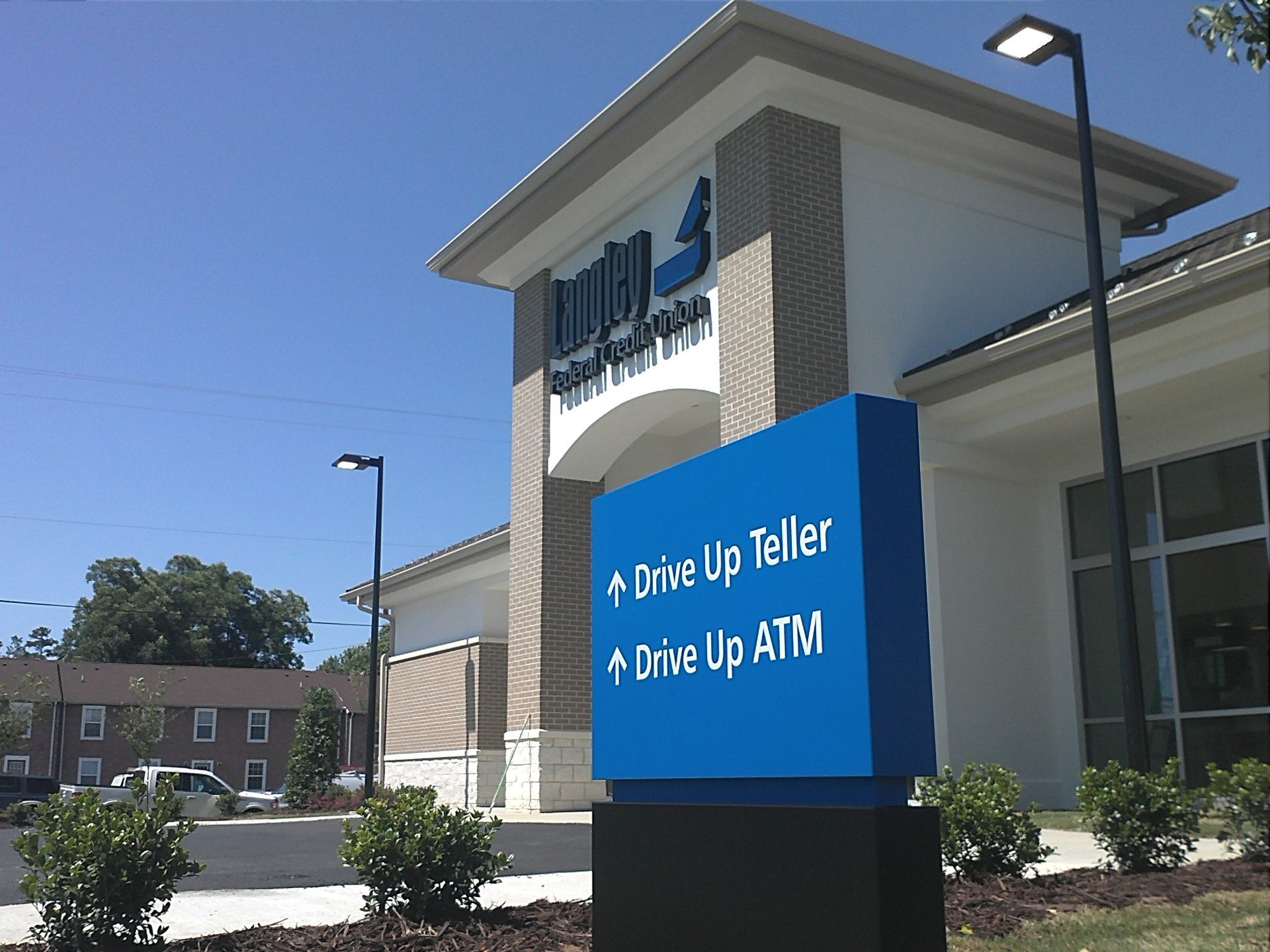 A drive up teller and drive up atm sign in front of a building