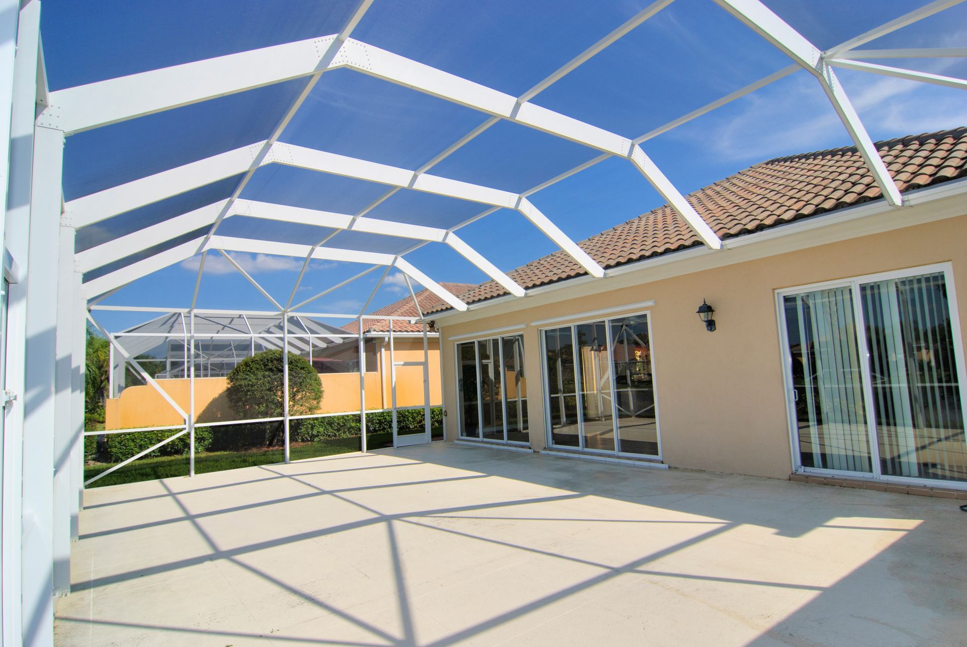 A spacious patio featuring a large screened roof, illuminated by natural light