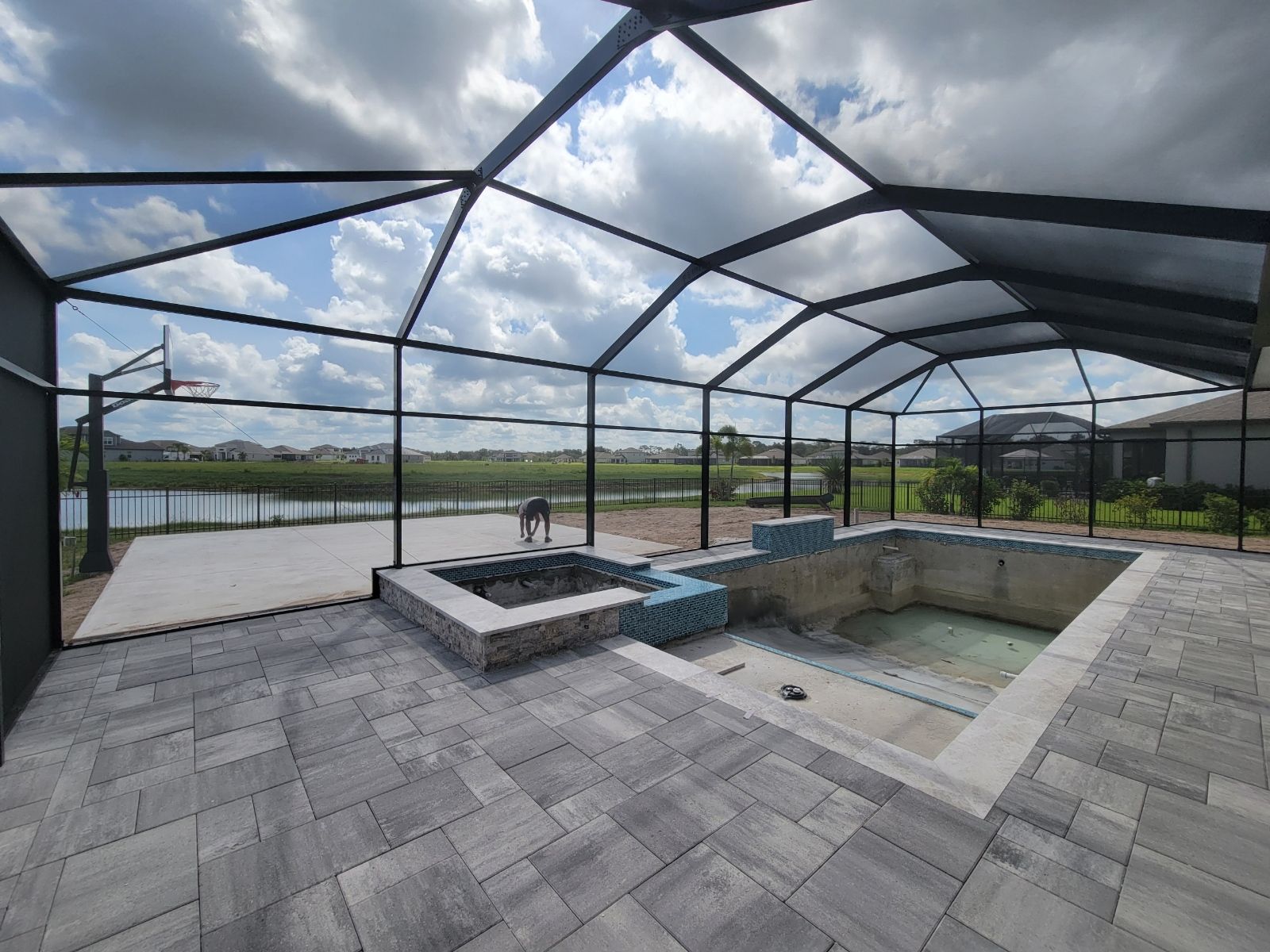 Covered patio with screened pool and hot tub under a cloudy sky.