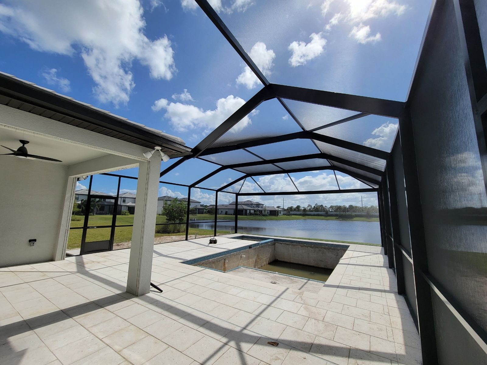 Sunny screened-in patio with tiled floor, pool, and view of open water and mountains
