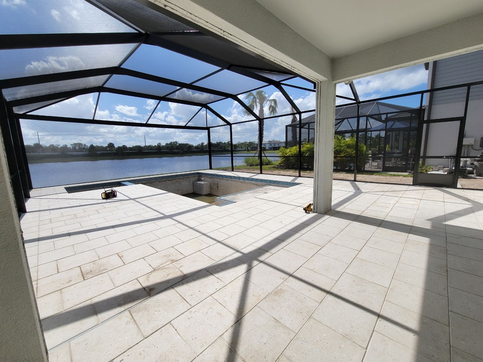 Covered patio with white tile floor, black screen enclosure, and a water view through the open side.