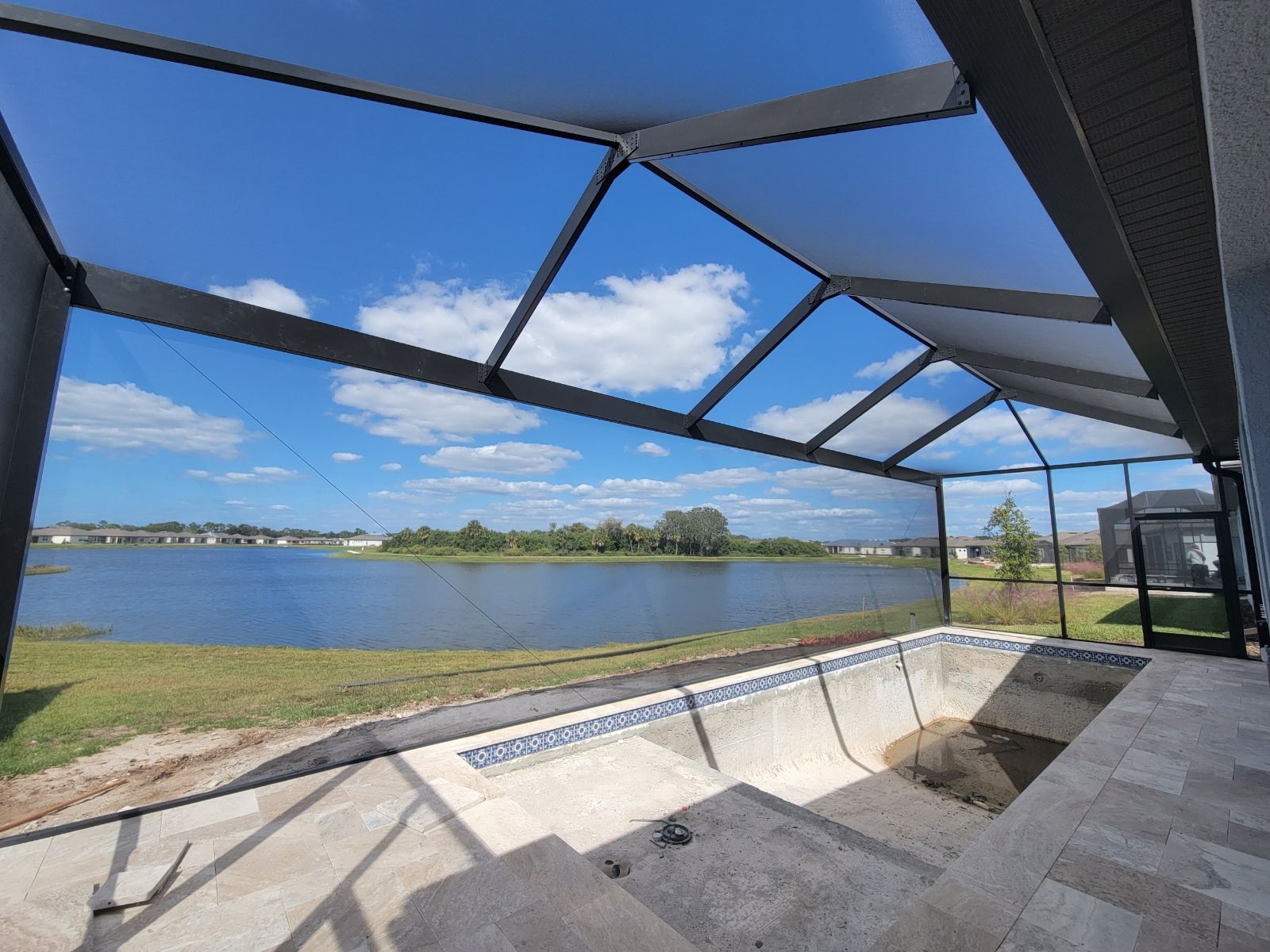 Shaded patio overlooking a calm lake under a blue sky with clouds
