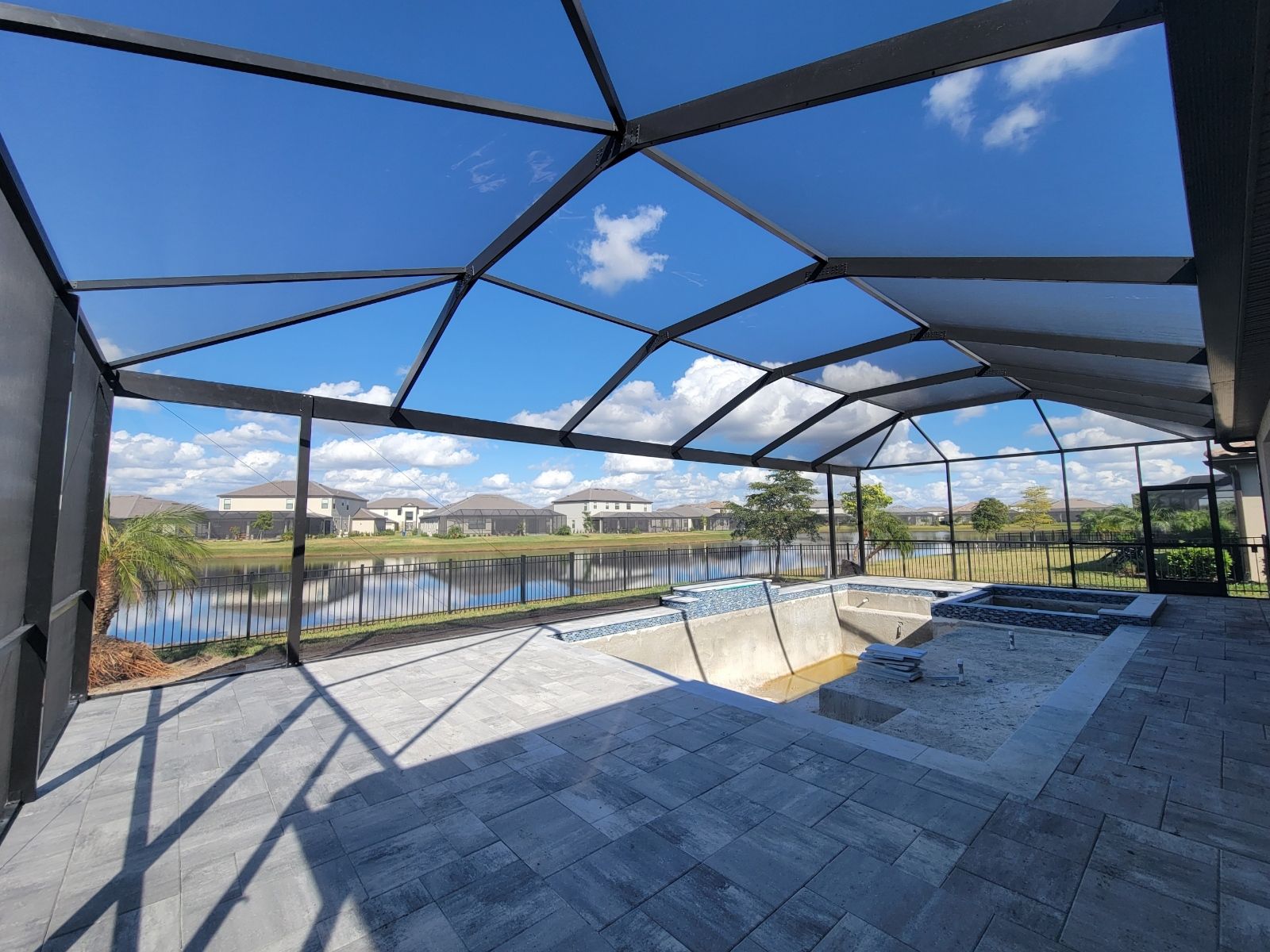 Modern covered patio with geometric mesh roof, river view, and blue sky over stone flooring