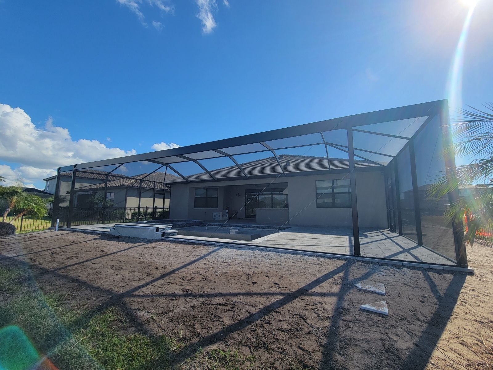 Modern building under construction with metal roof framing and gravel foreground under a bright blue sky