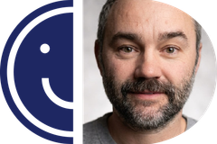 A minimalist, two-tone blue and light grey icon of a smiling face split vertically down the middle, with inverted colors on each side forming a circular emblem.