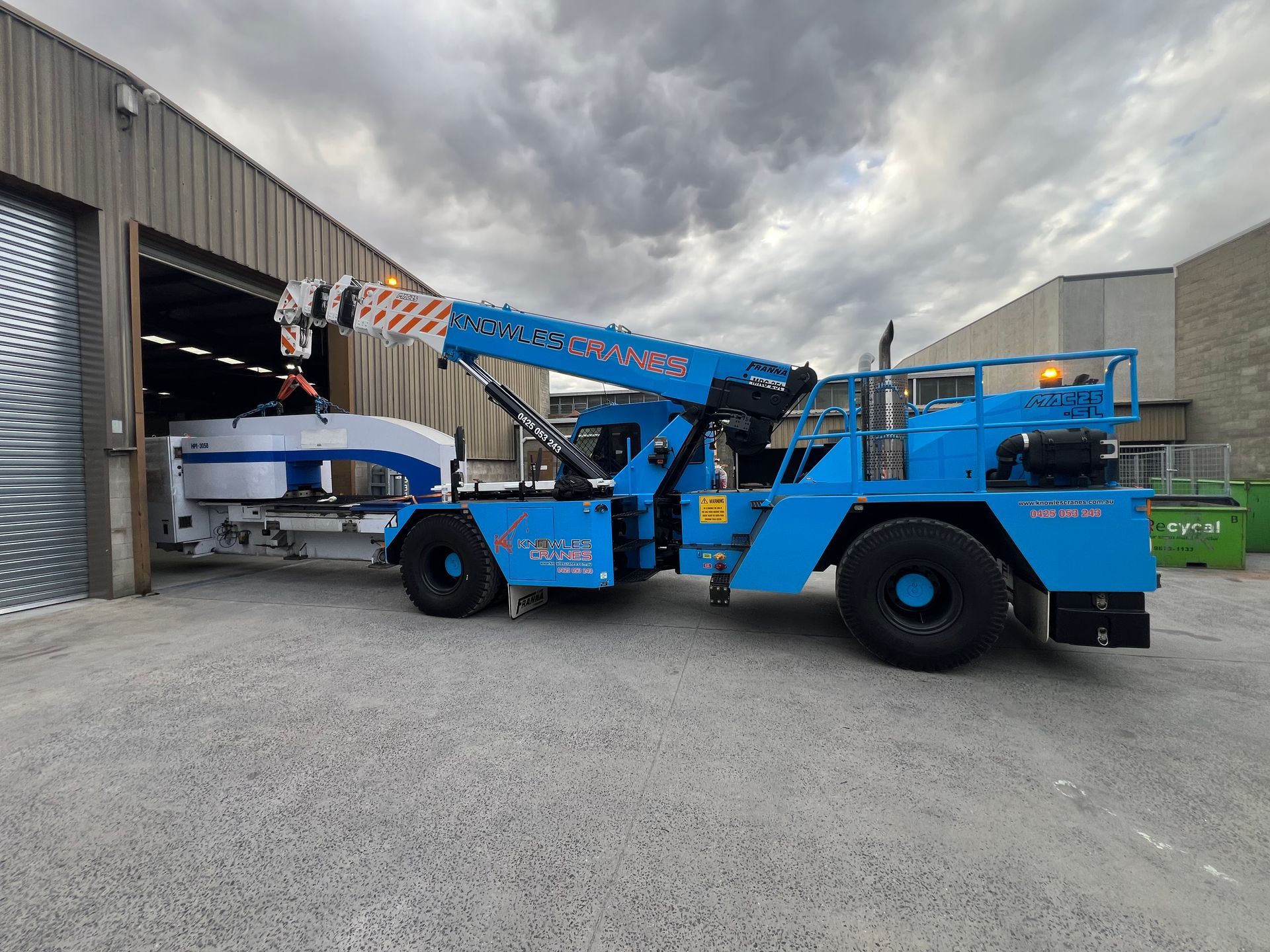 Franna crane moving large industrial equipment out of a factory unit