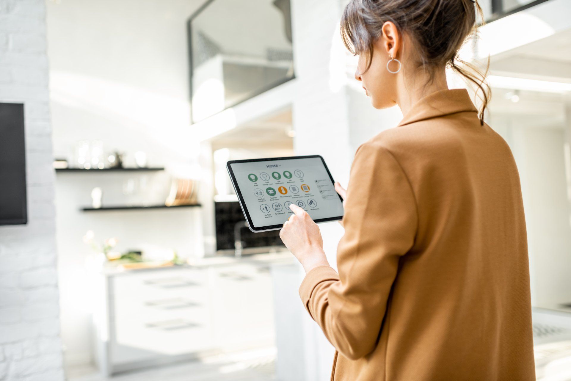 Woman controlling smart home devices using a digital tablet with launched application in the white living room.