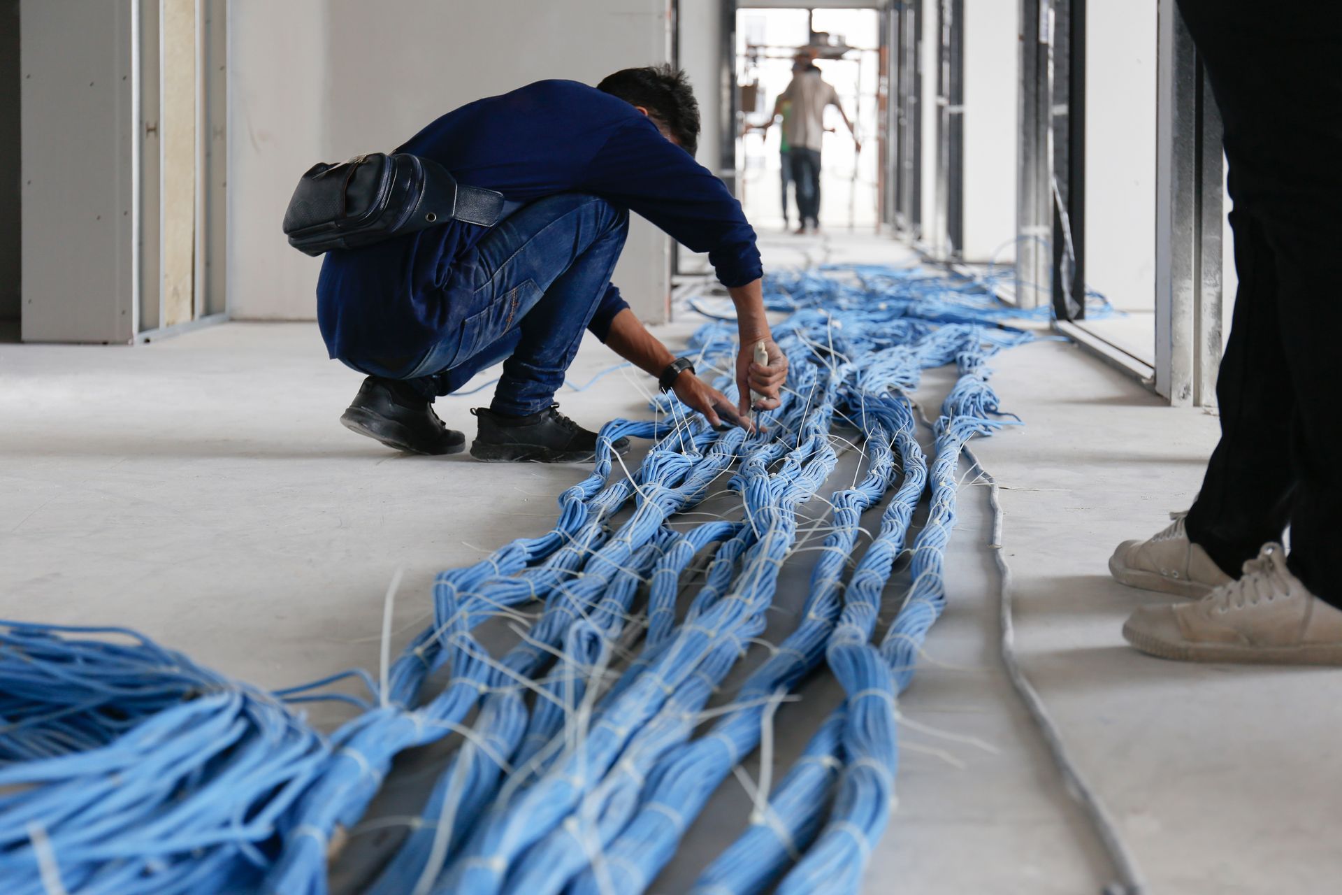 Worker wiring LAN cable at construction site
