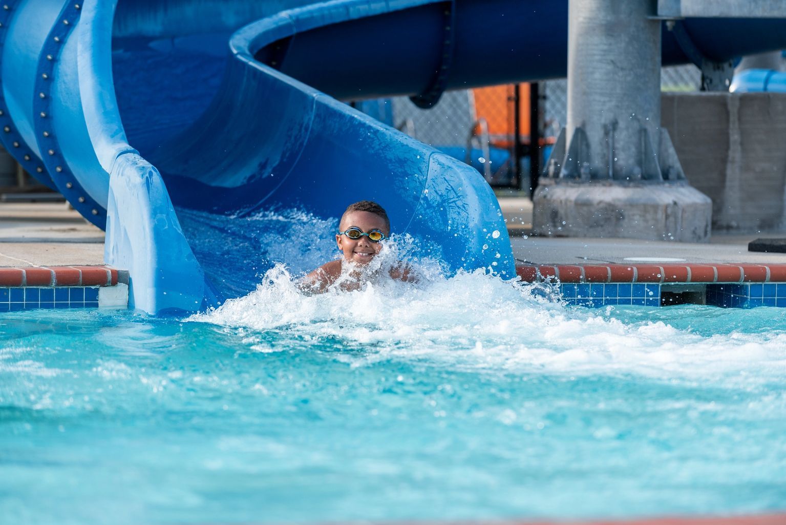 Person splashing down a blue water slide into a pool at an indoor water park