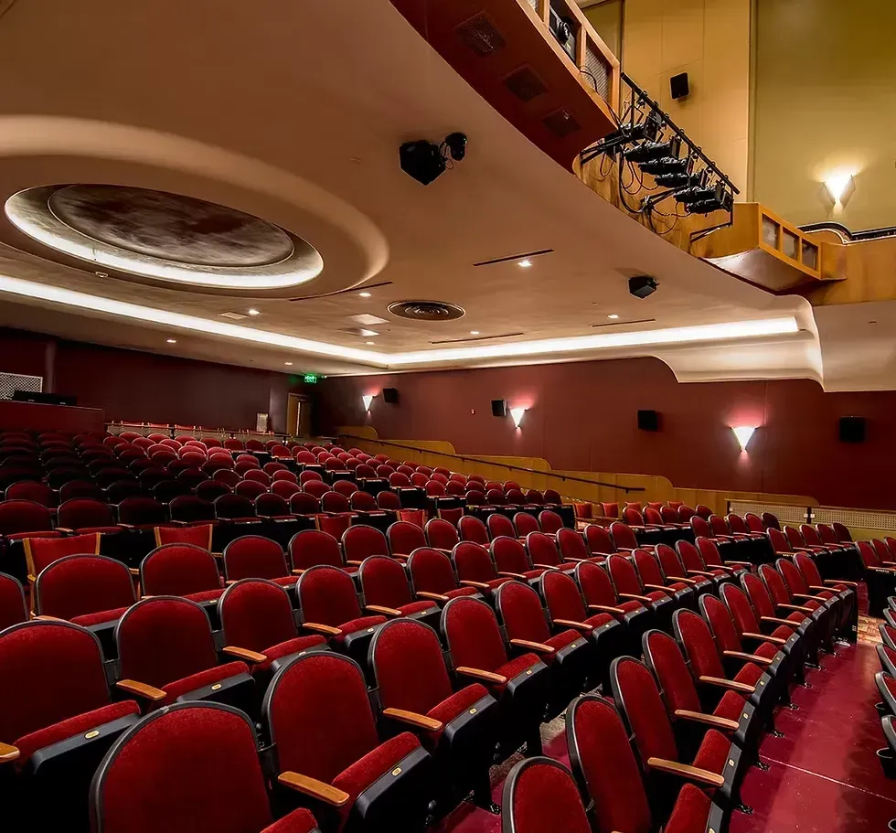 Empty theater auditorium with red seats, ornate ceiling, and balcony seating