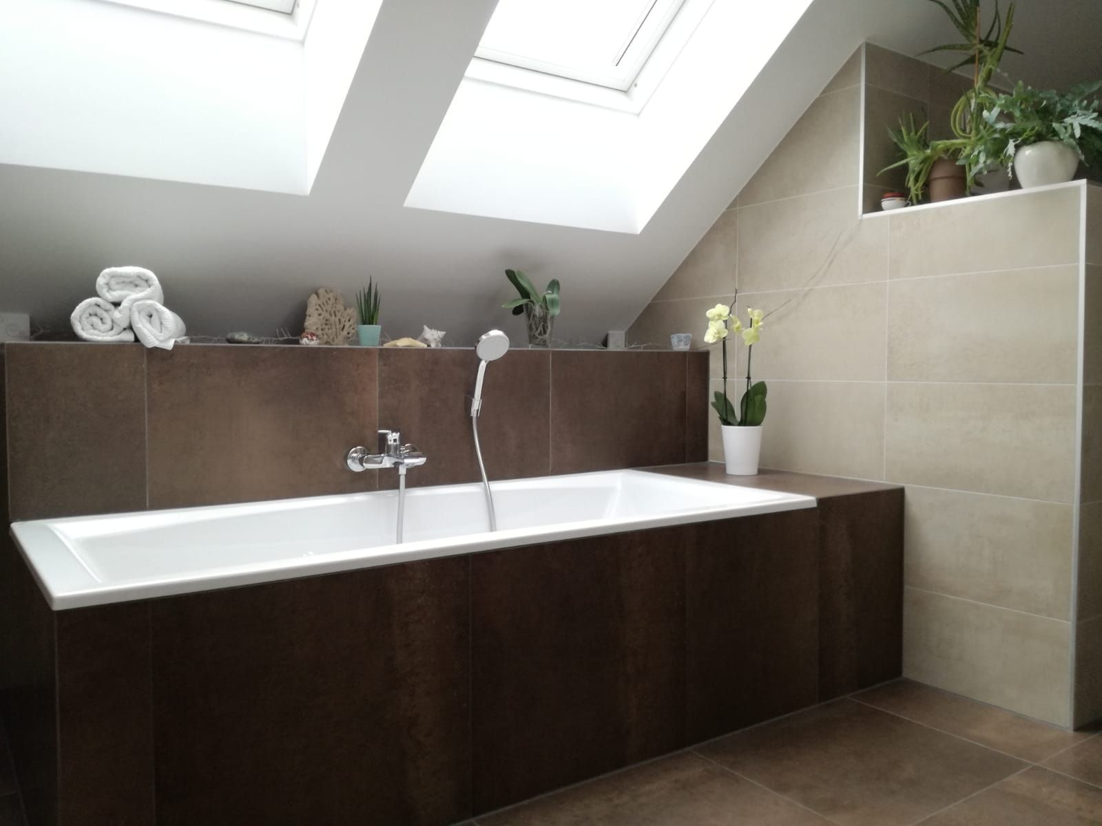 Eine Badewanne in einem Badezimmer unter Dachfenstern darüber.