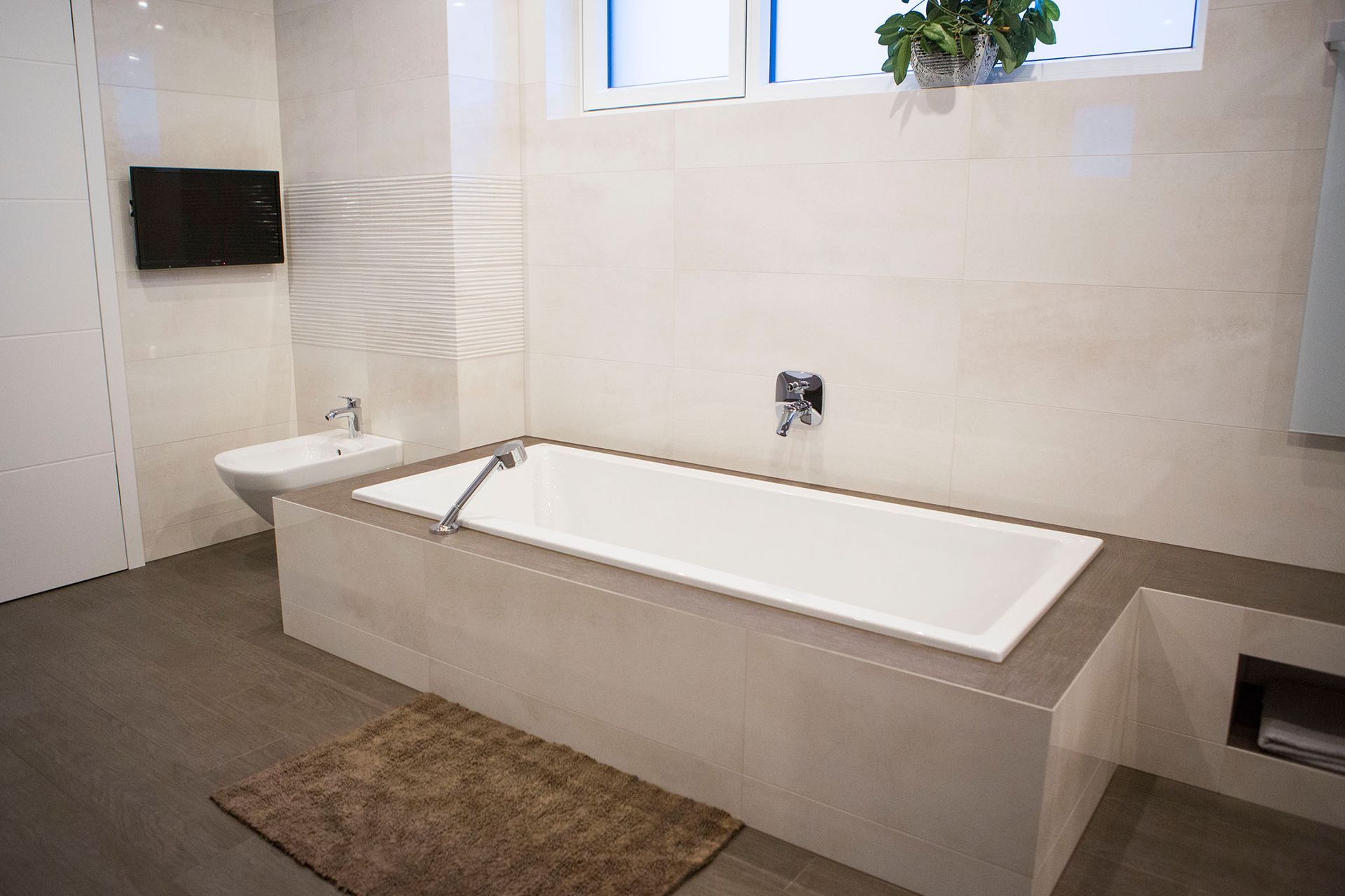 In der Mitte des Badezimmers befindet sich eine Badewanne mit Fliesen.