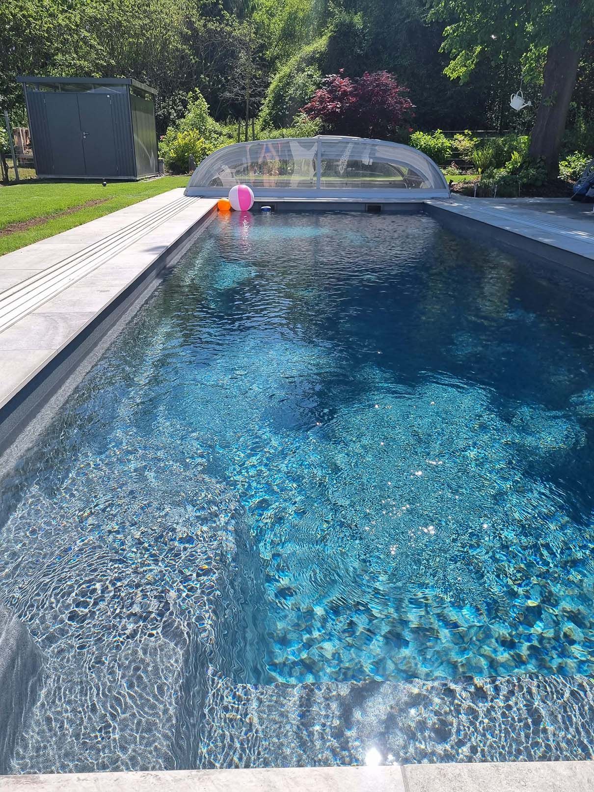 Ein großes Schwimmbecken mit klarem, blauem Wasser und einem rosa Ball darin.