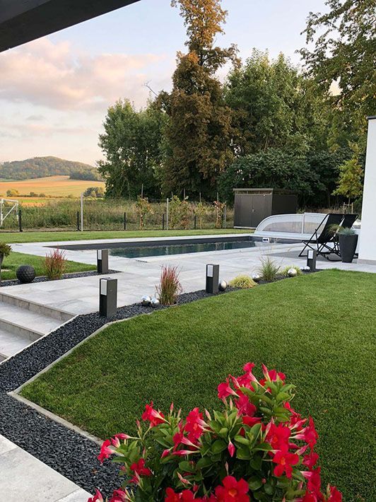 Ein großer Swimmingpool ist von üppigem grünem Rasen und Blumen umgeben.