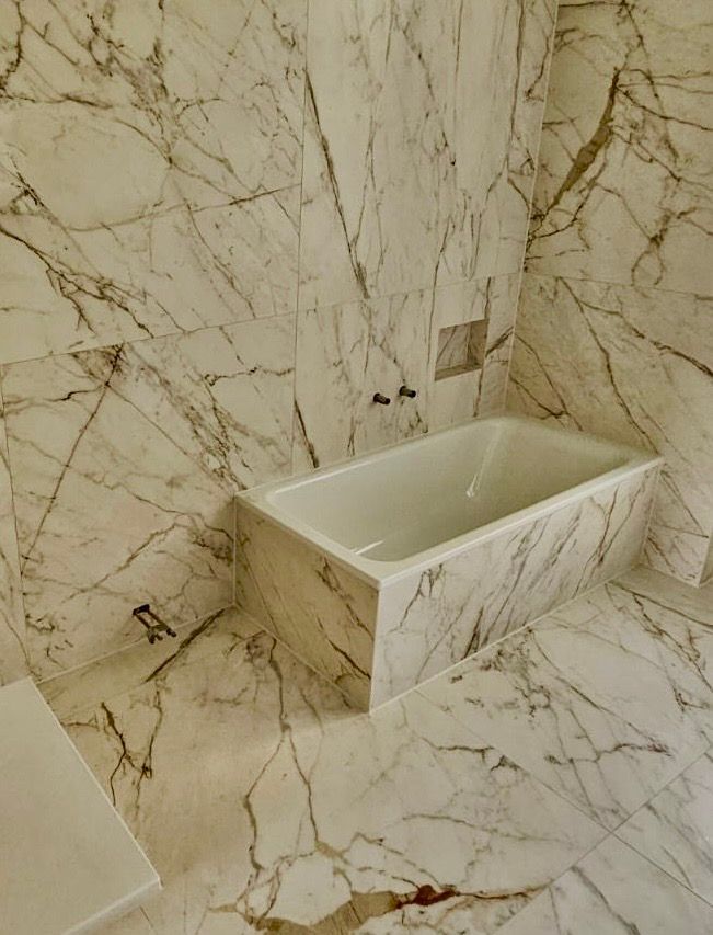 Ein Badezimmer mit Marmorfliesenwänden und -böden und einer Badewanne.