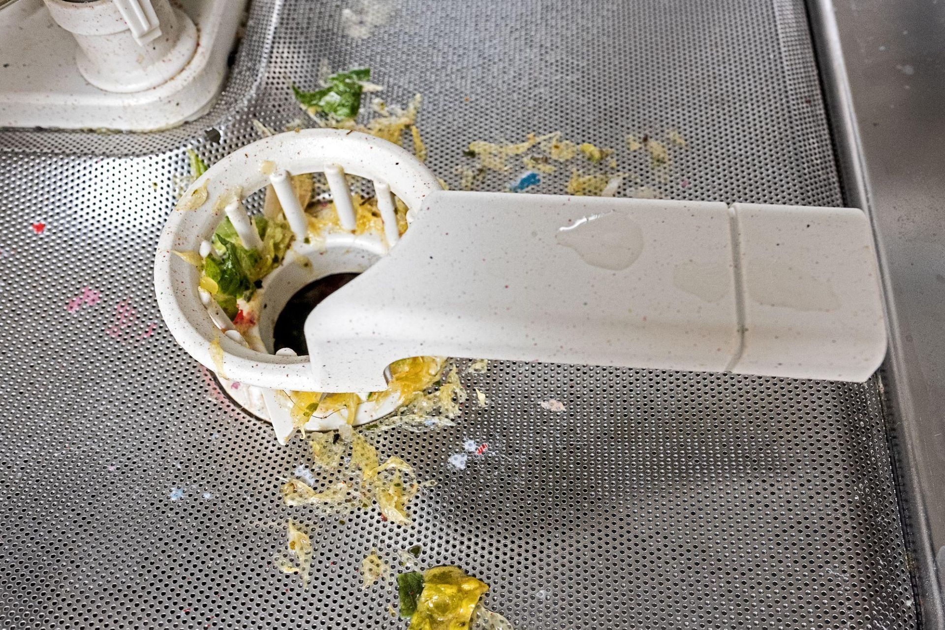 Dishwasher drain with bits of food and debris trapped in it Dishwasher drain with bits of food and debris trapped in it