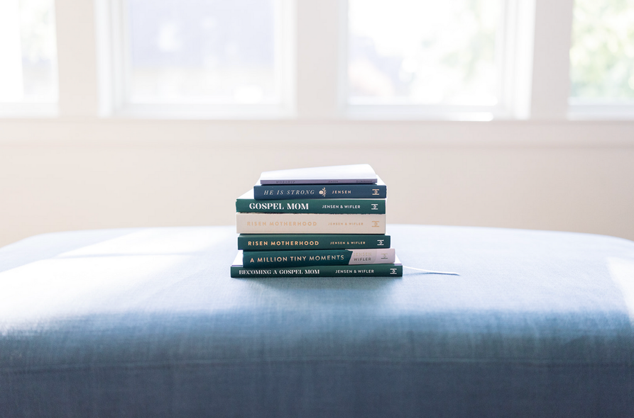 Stack of books on a bed by a bright window