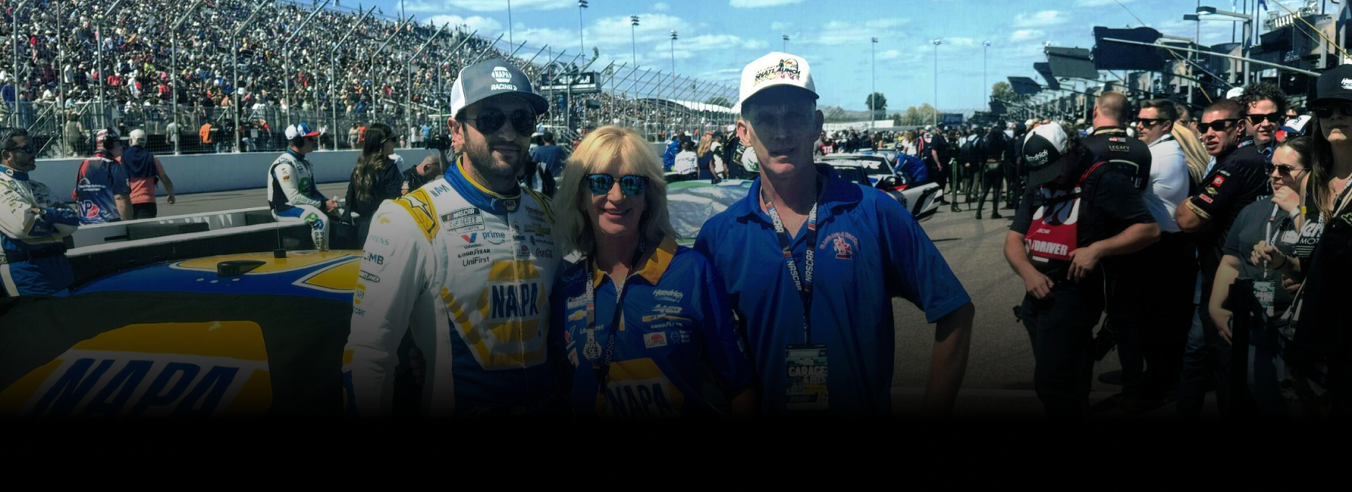 Three people posing at a race. Two are wearing team attire, with a race car behind them. | St. Louis Auto & Truck Repair