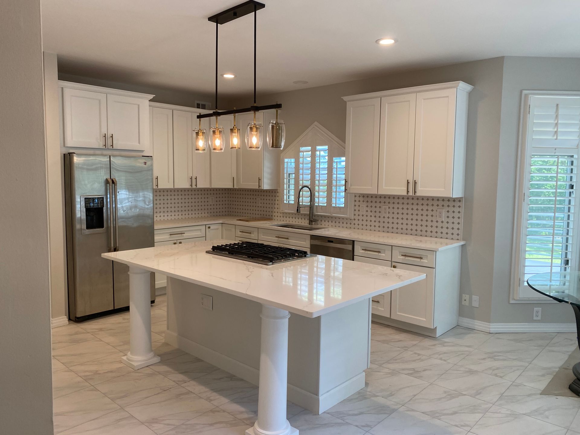 East Brunswick NJ newly remodeled kitchen with island design and stainless steel appliances, modern lighting and white cabinets.