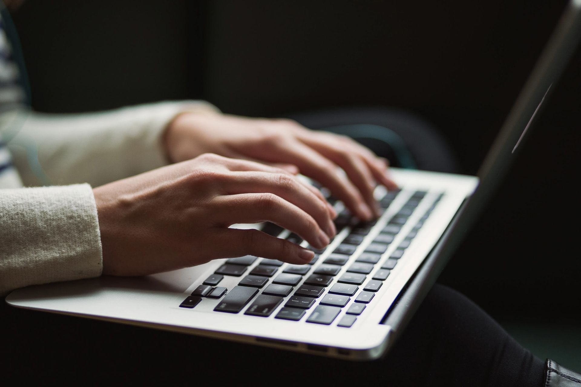 Hands typing on a laptop keyboard.