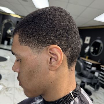 A man is getting his hair cut at a barber shop.