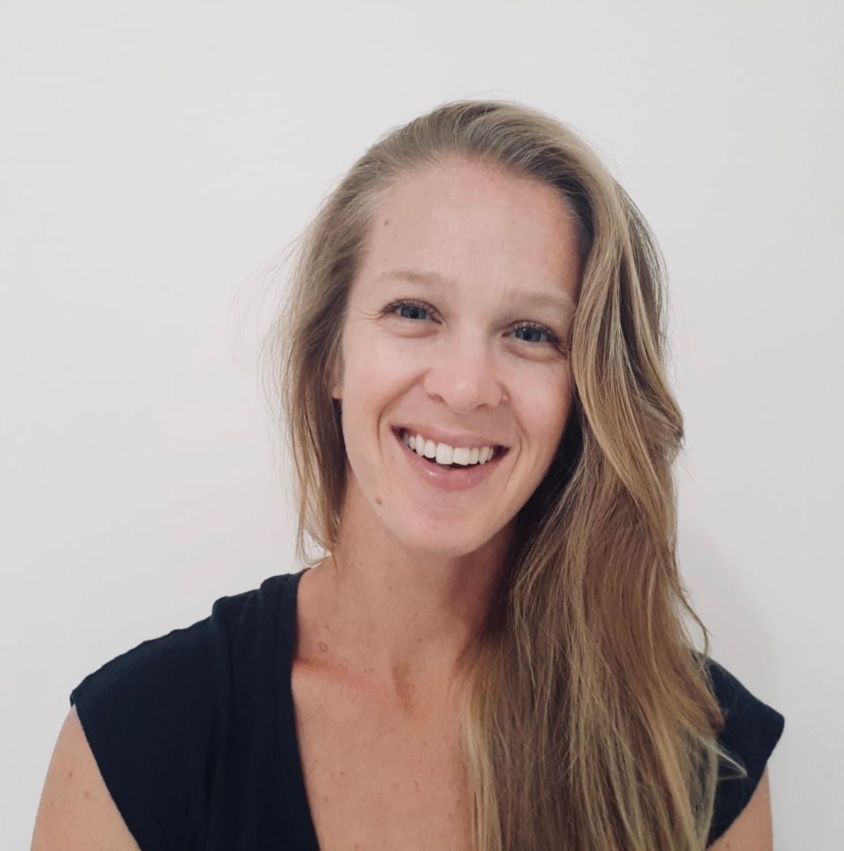 Smiling woman with long blonde hair against a light gray background