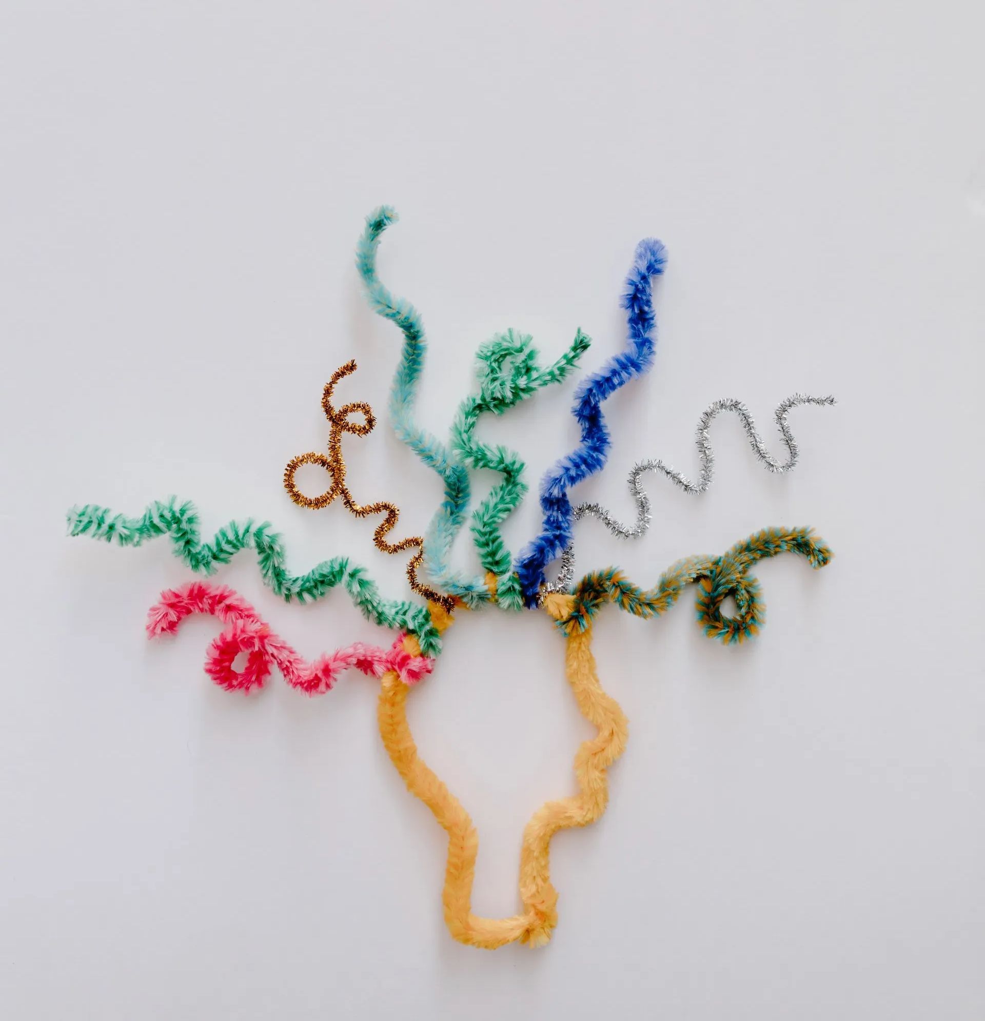 Colorful curly pipe cleaners arranged like a flower or bursting fountain on a white background