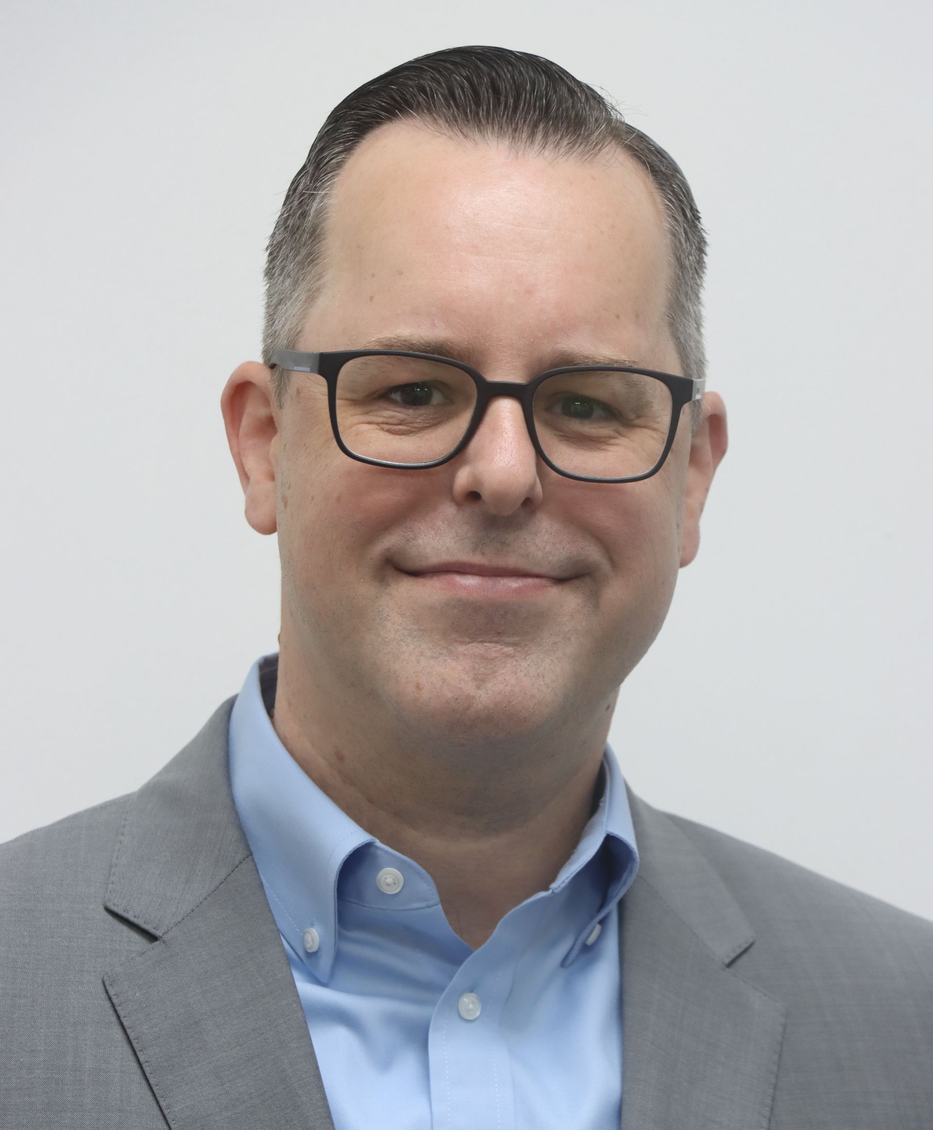 A man in a suit and tie is smiling for the camera