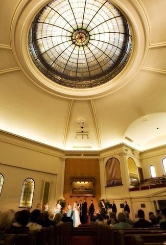A bride and groom are getting married in a church with a stained glass dome.