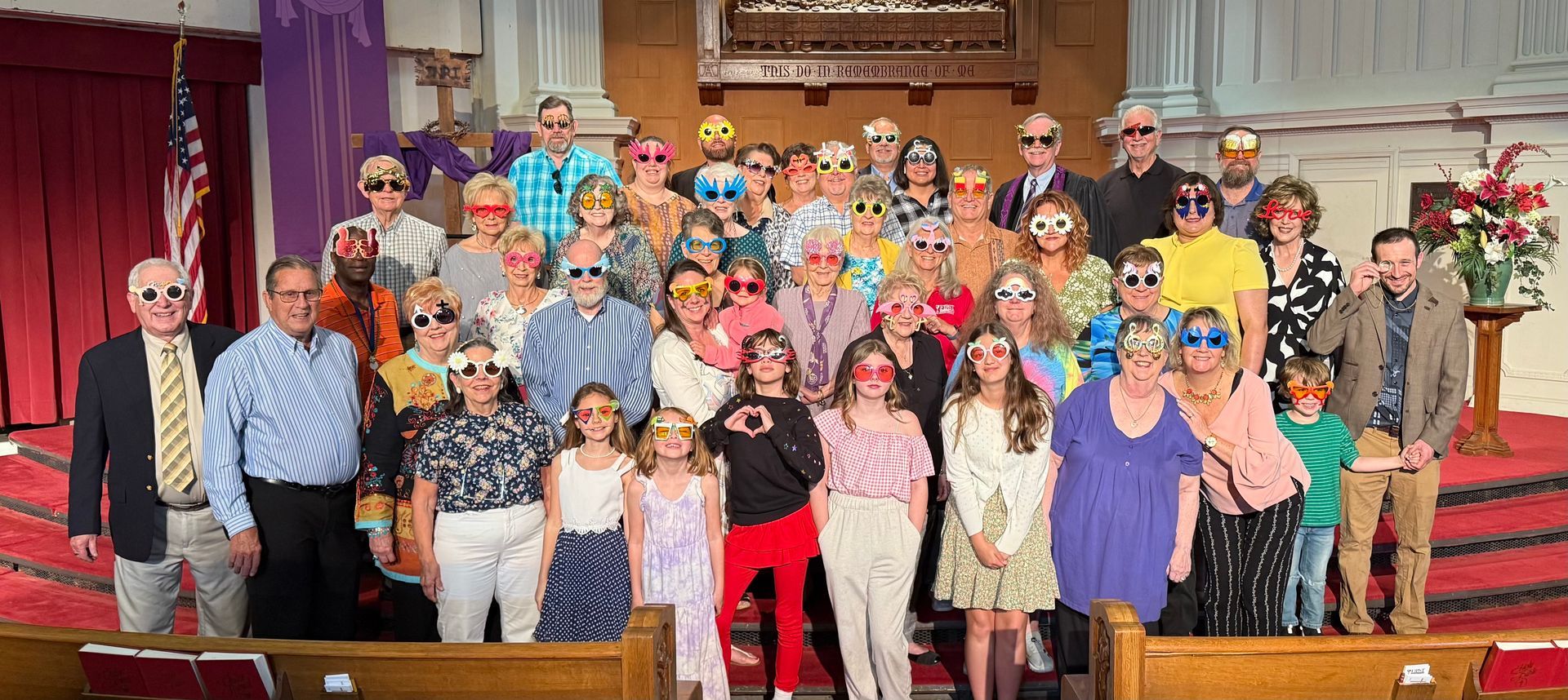 Group of people wearing novelty sunglasses posing in a church.