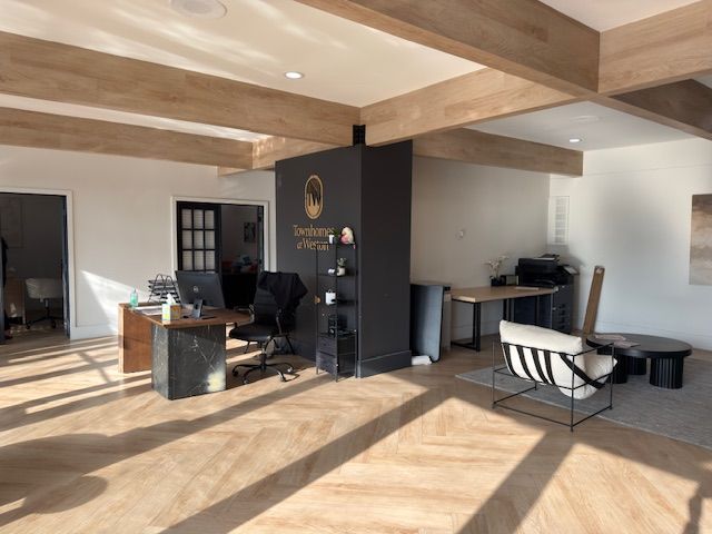 Modern open office with desks, chairs, and a lounge area under wood-beam ceilings