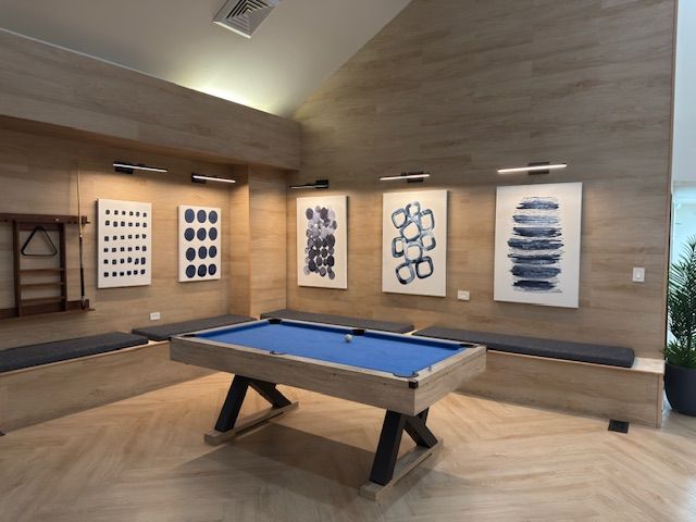 Modern game room with a blue pool table and framed abstract art on wood-paneled walls
