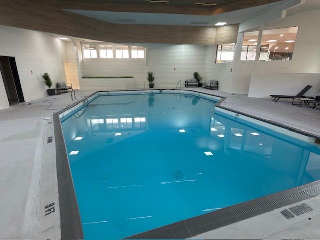 Indoor swimming pool with clear blue water in a bright, modern recreation room