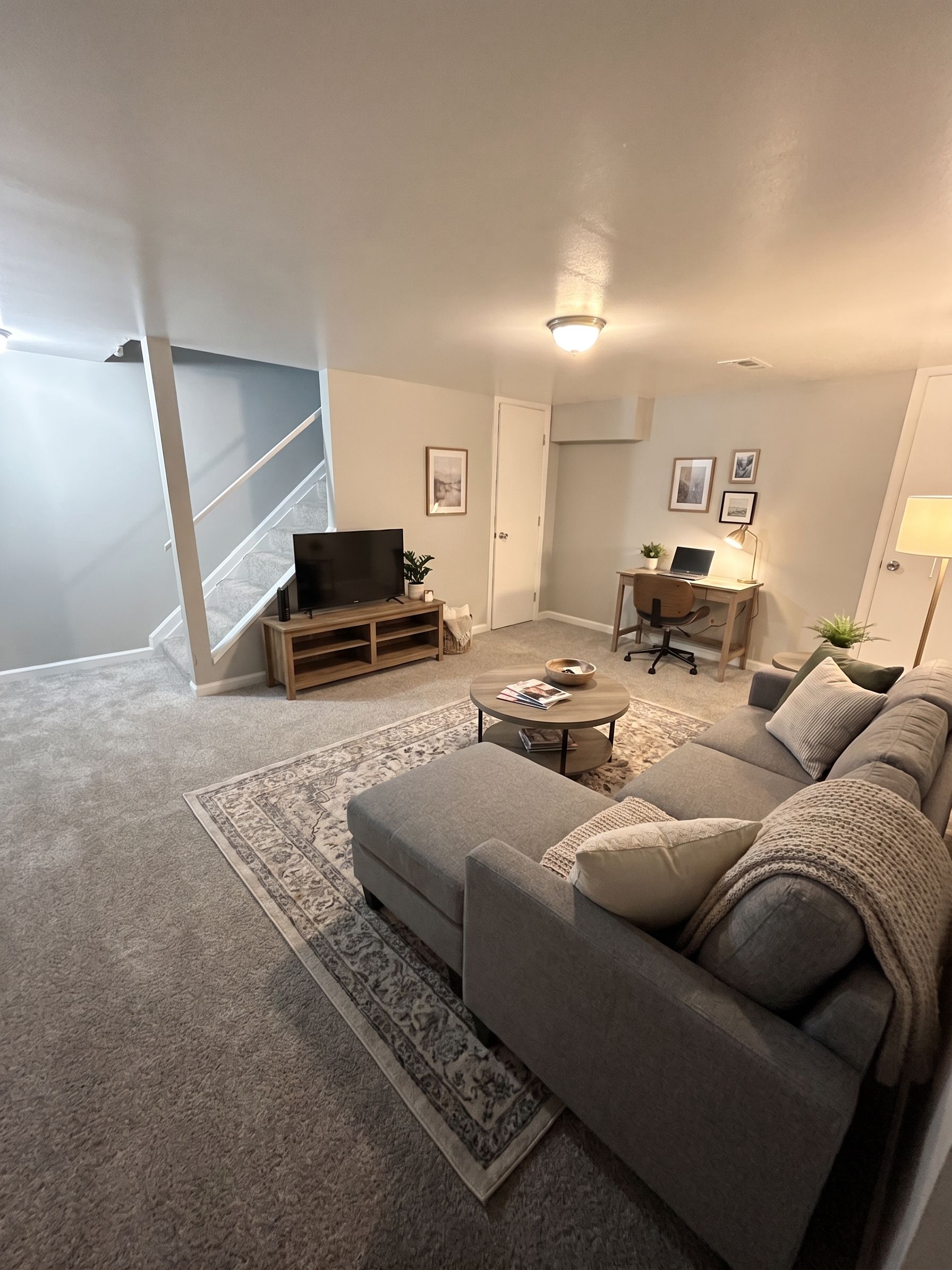Cozy living room with gray sectional sofa, TV on stand, coffee table, and warm lighting