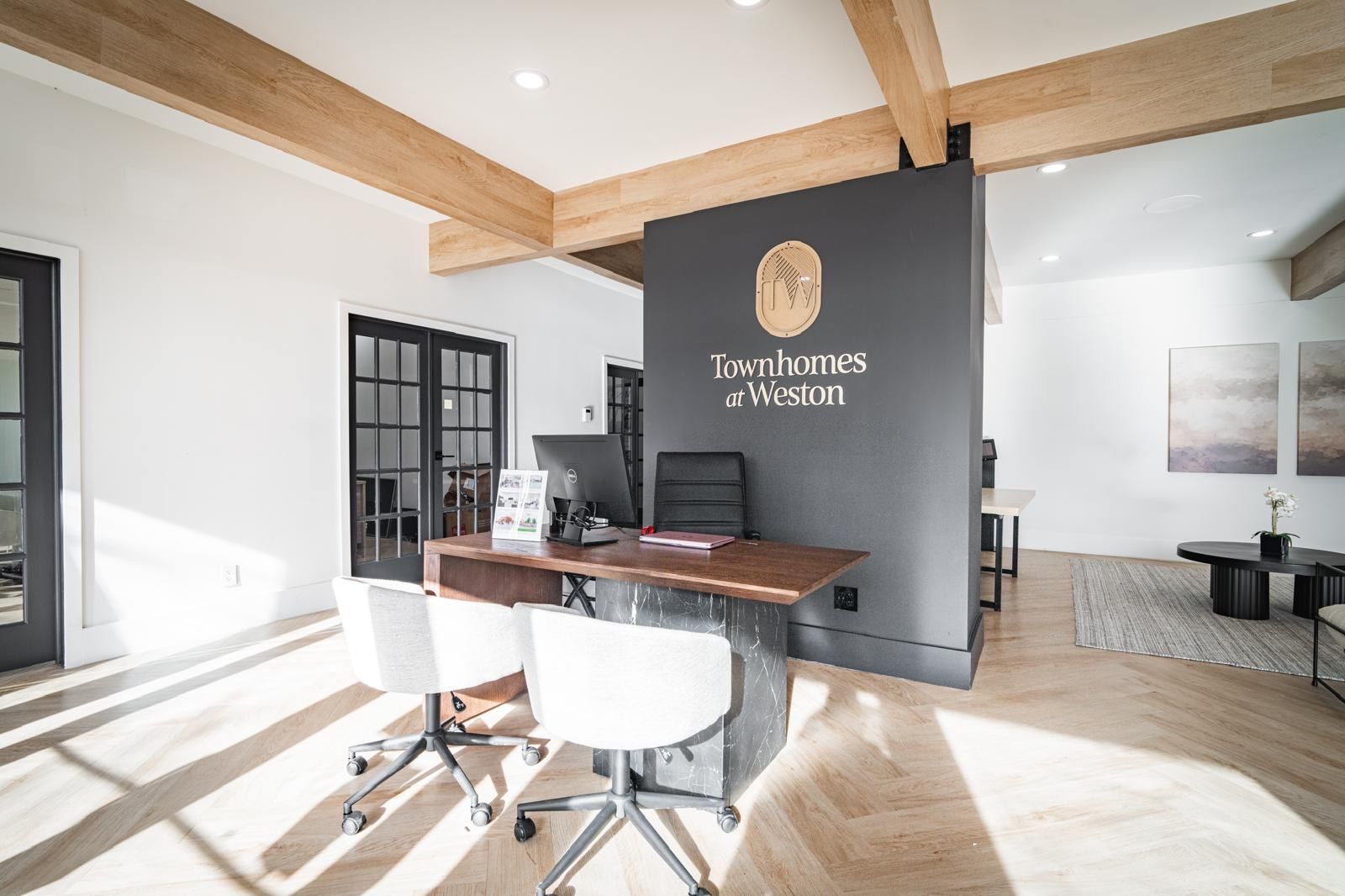 Modern office reception with wood beams, black accent wall, and white chairs in bright natural light