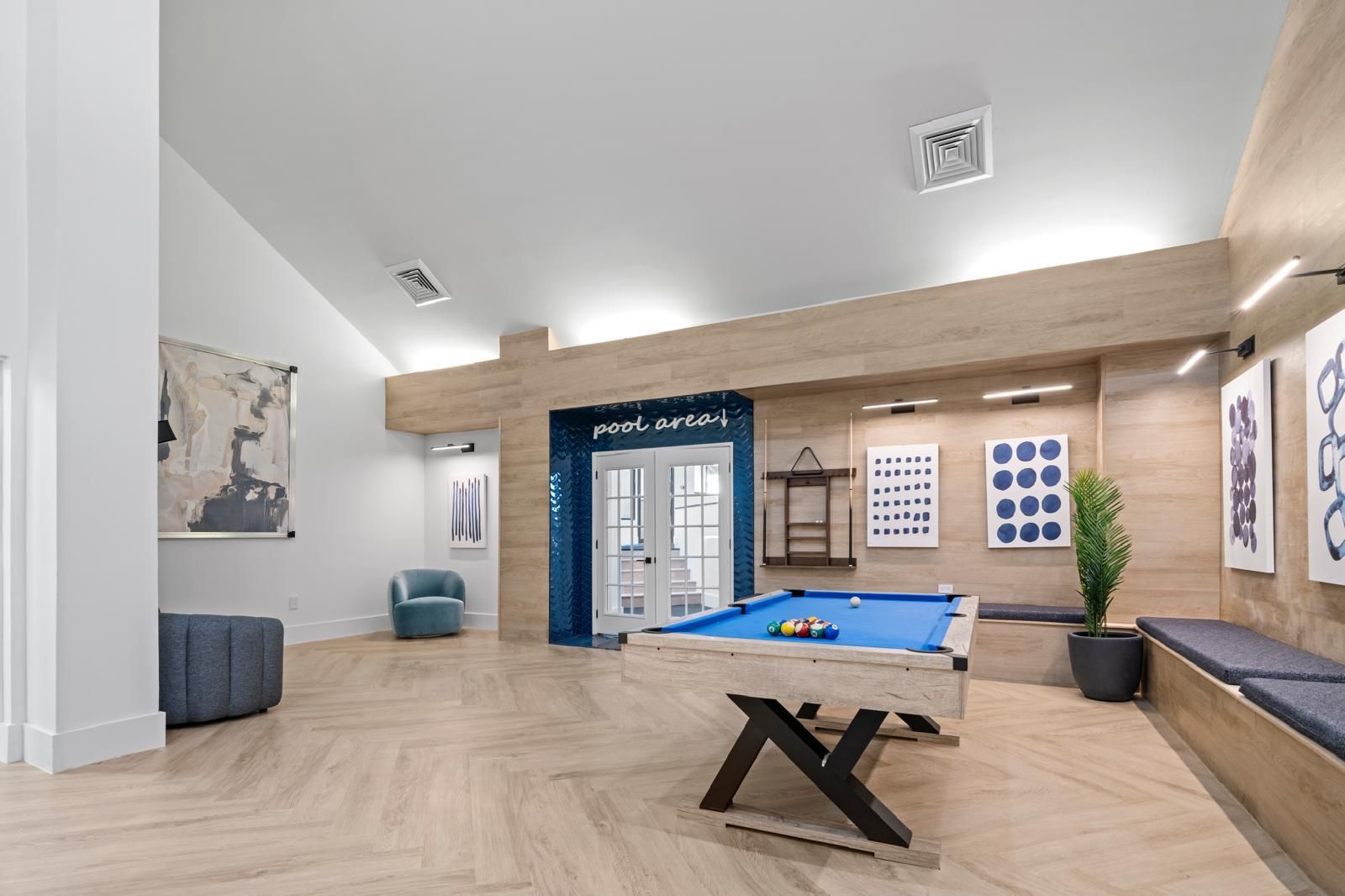 Bright modern lounge with blue sectional, low table, wood accents, and large windows