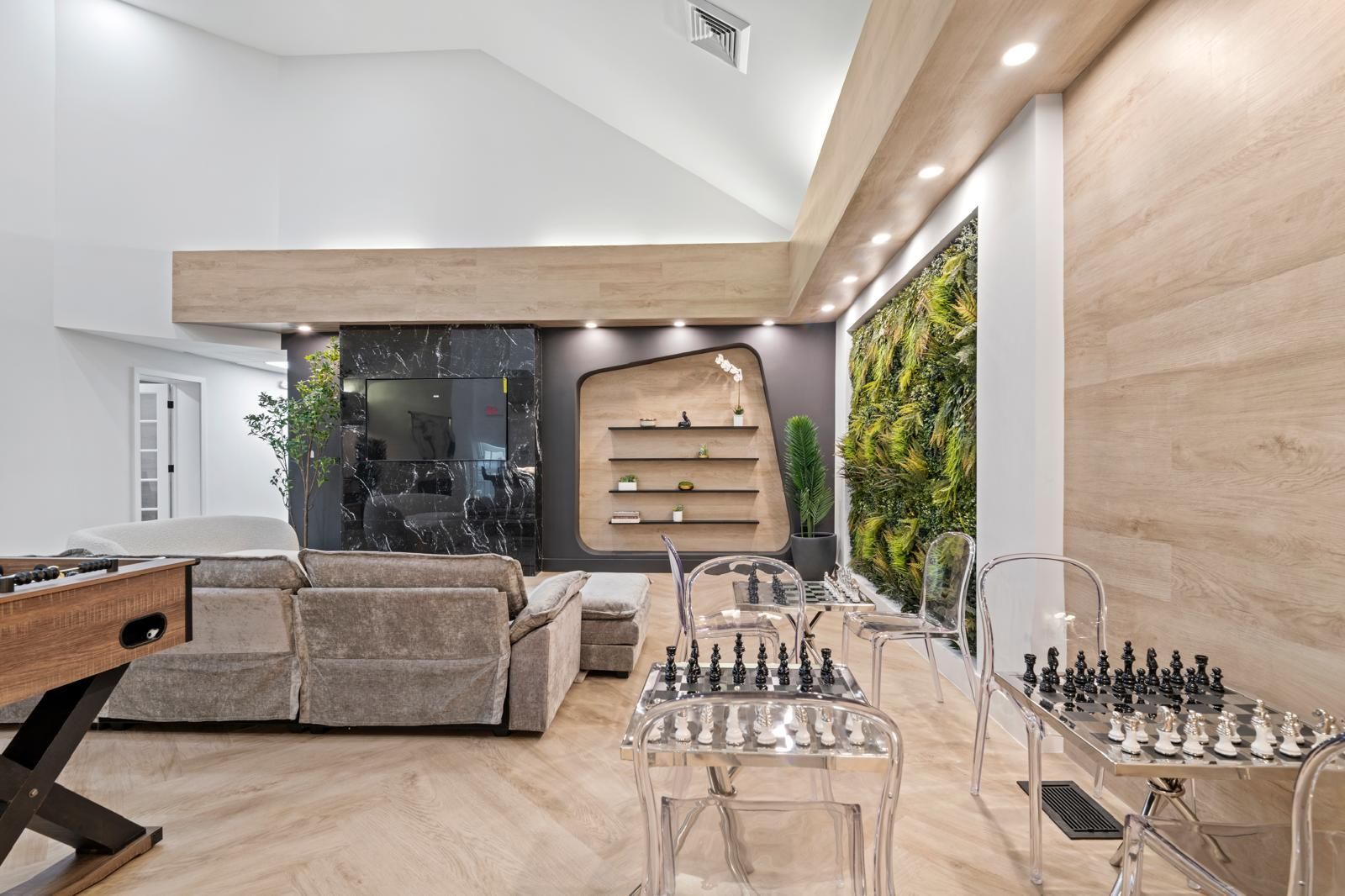 Modern living room with sectional sofa, wood accents, and chess sets on clear tables