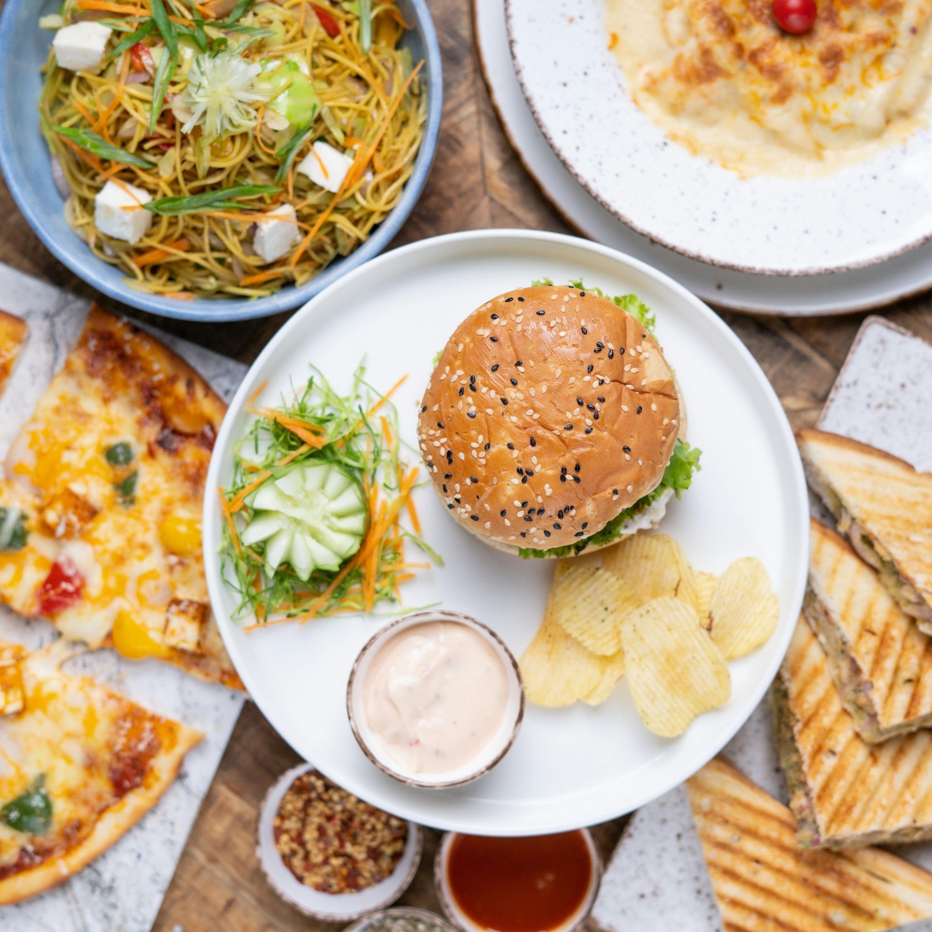 Assorted sandwiches, salad, chips, and dips arranged on a table in a top-down view
