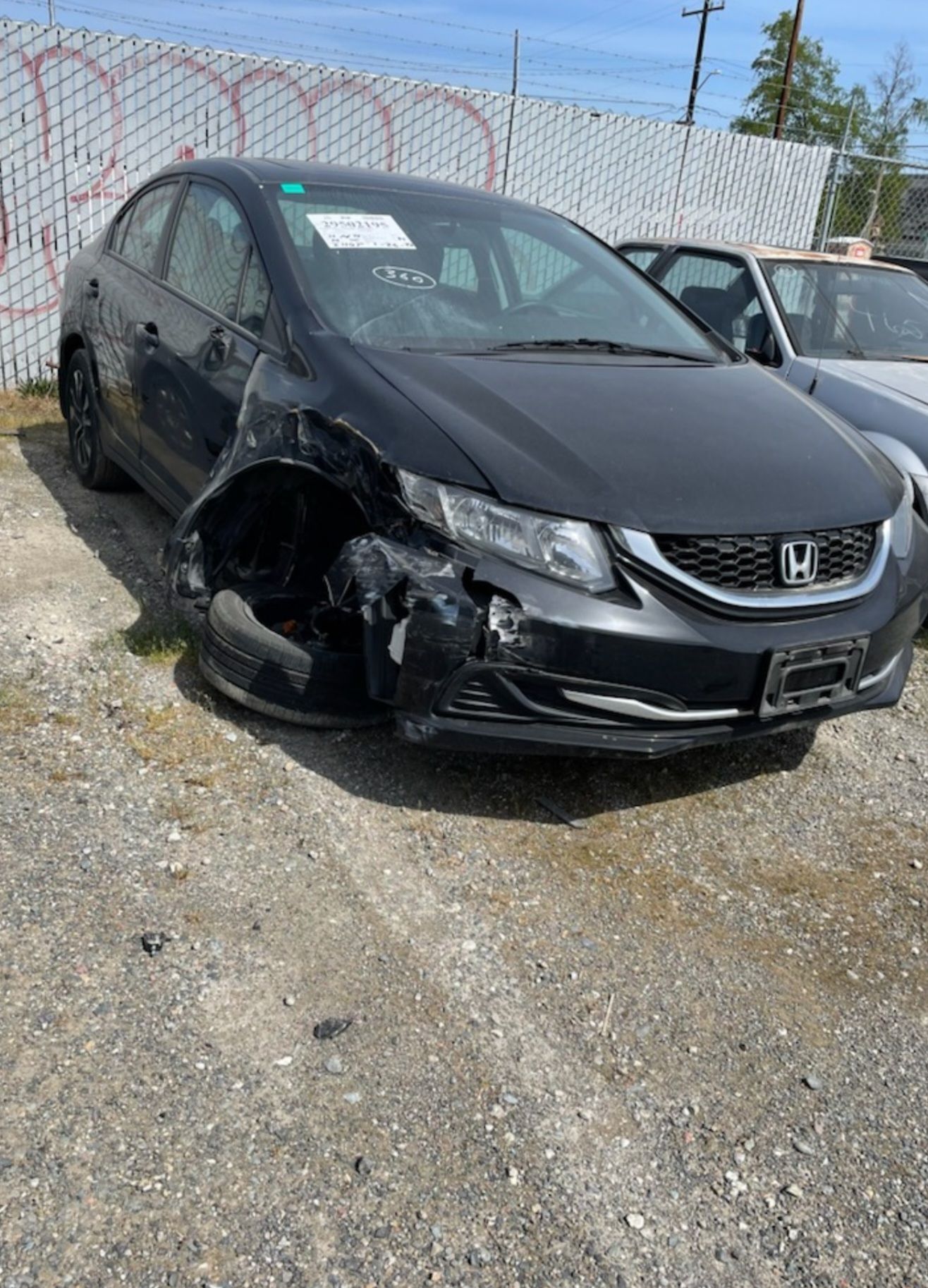 A black honda civic with a damaged front end is parked in a lot.