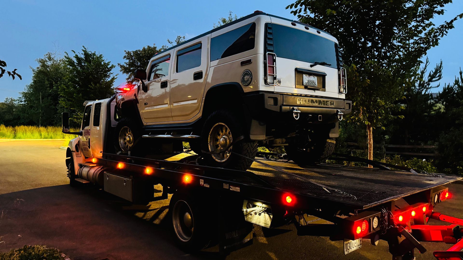 A tow truck is towing a car on the side of the road.