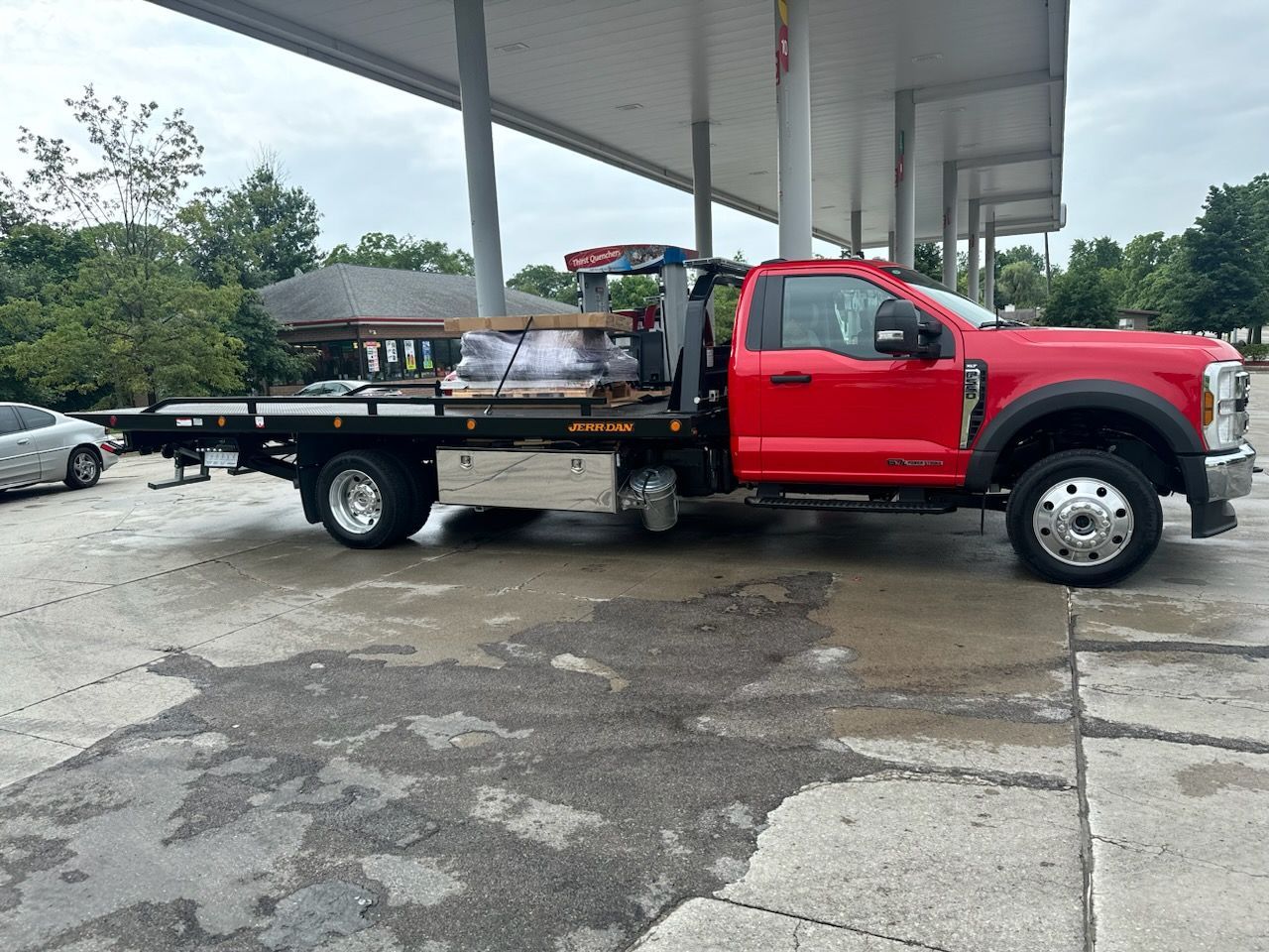 A tow truck is pulling a trailer with a camper on it.