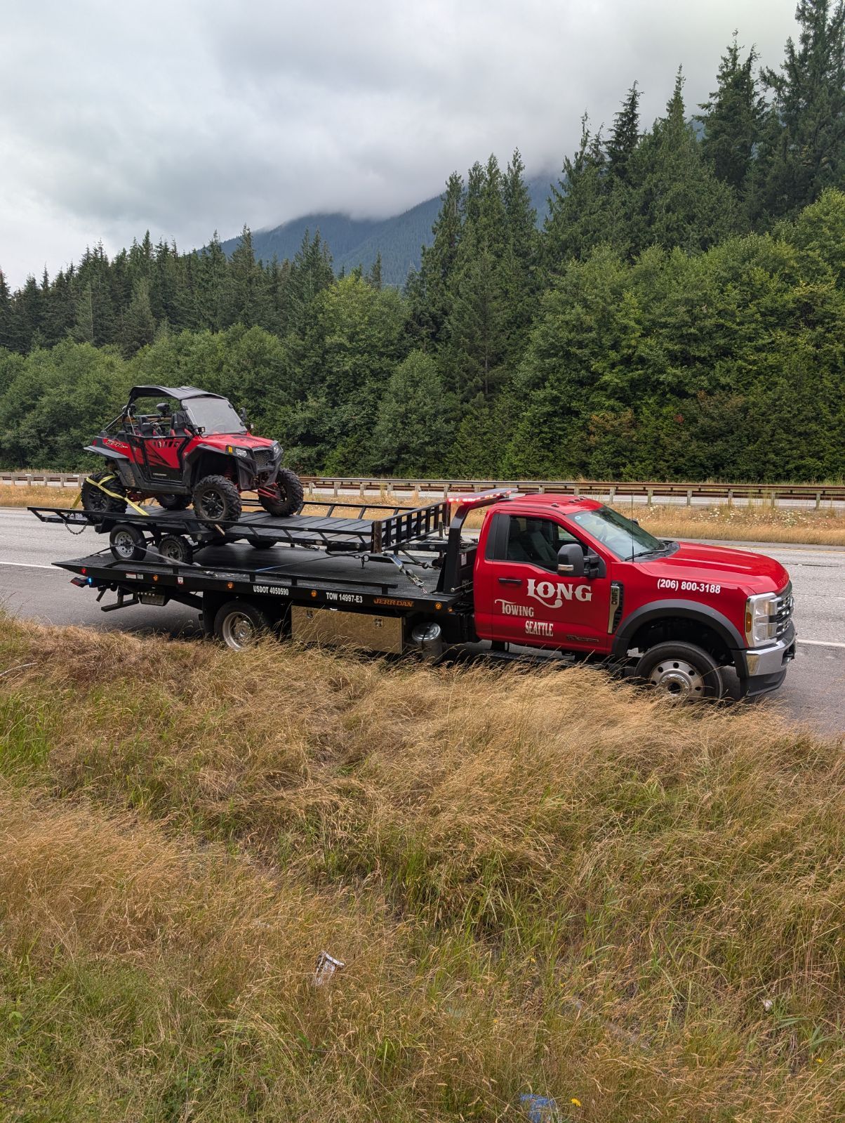 A tow truck is towing a motorcycle in the snow.