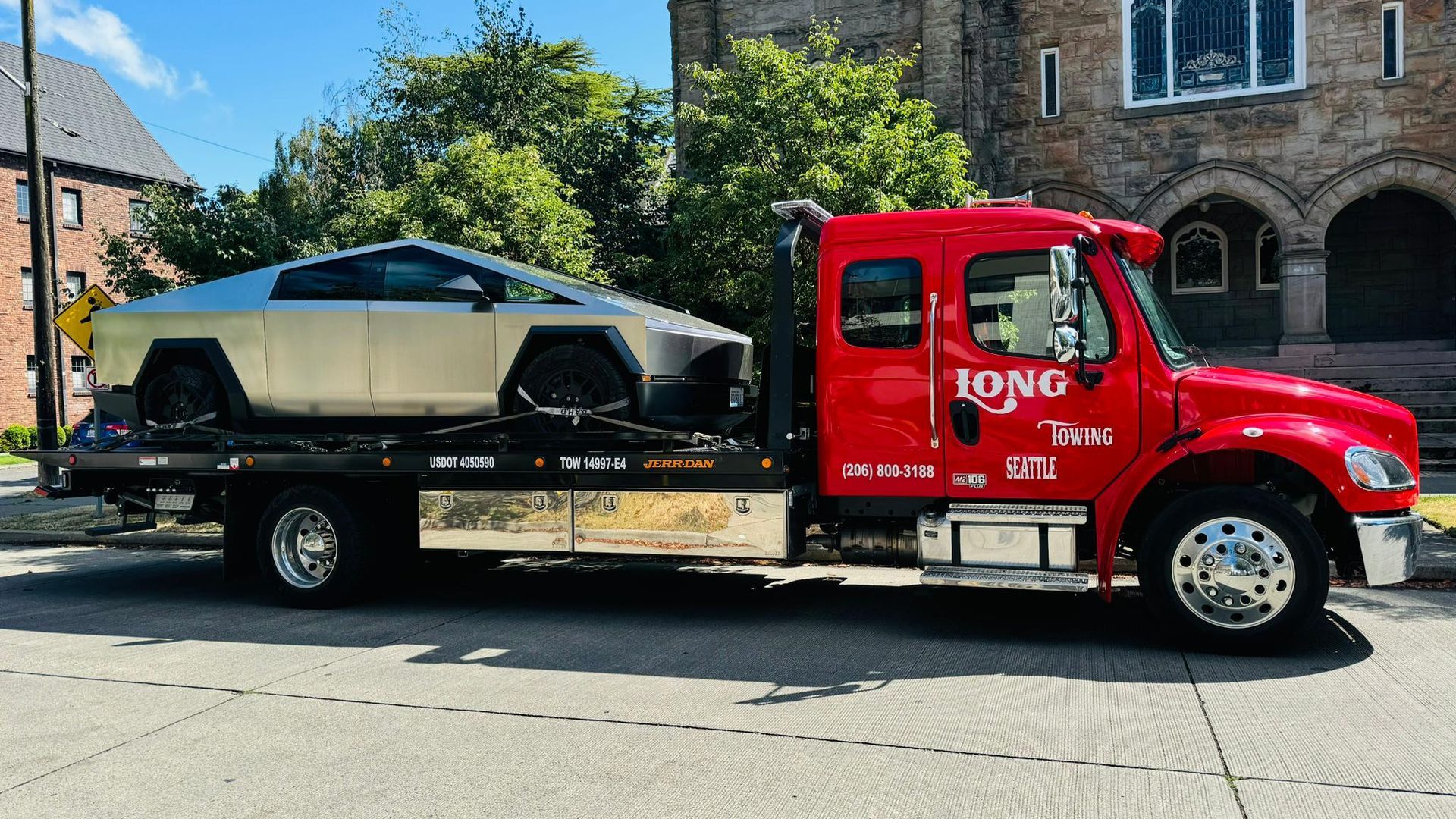 A white tow truck is towing a white car in a parking lot.