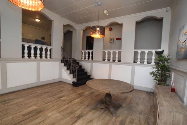 Empty room with wood floors, round table, staircase, decorative alcoves, and light fixtures.