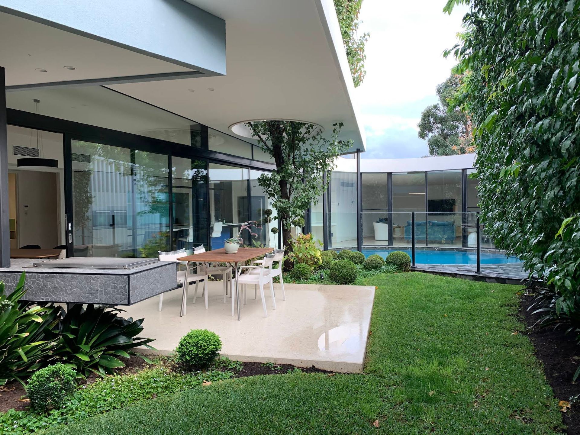 Modern Patio With Outdoor Dining Table Beside a Pool and Glass-walled House — KM Custom Homes In Mount Eliza, VIC
