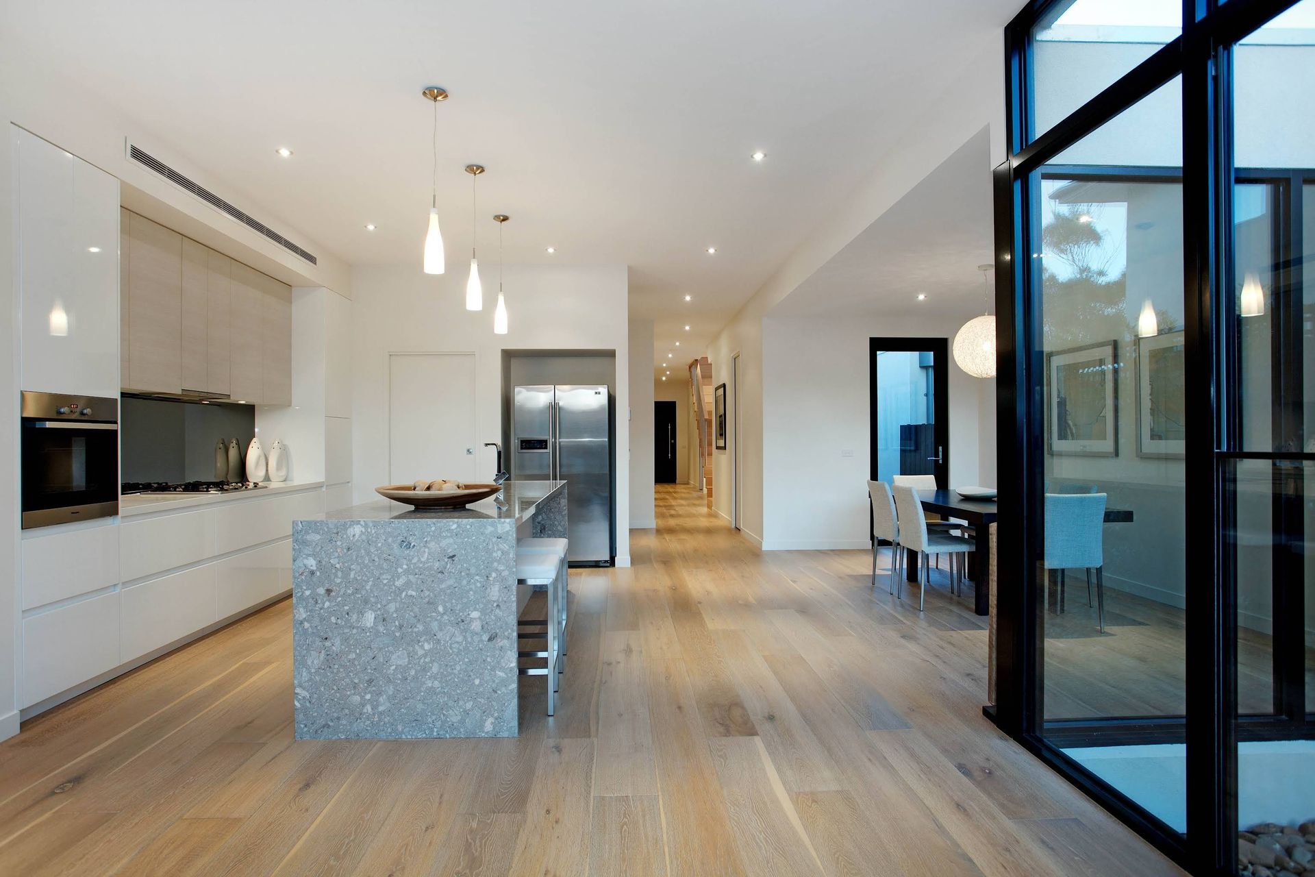 Modern Kitchen and Dining Area With White Cabinetry and Large Glass Doors — KM Custom Homes In Mount Eliza, VIC