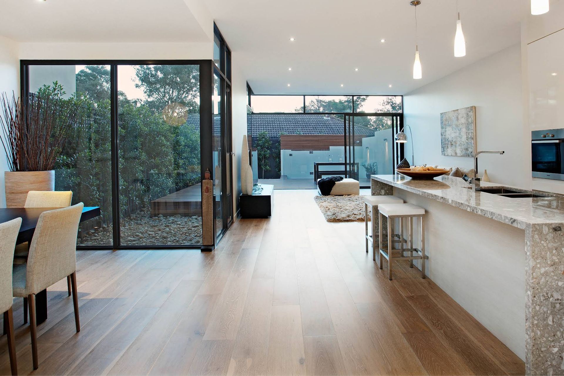 Modern Kitchen and Dining Area With White Island and Large Sliding Glass Doors — KM Custom Homes In Mount Eliza, VIC