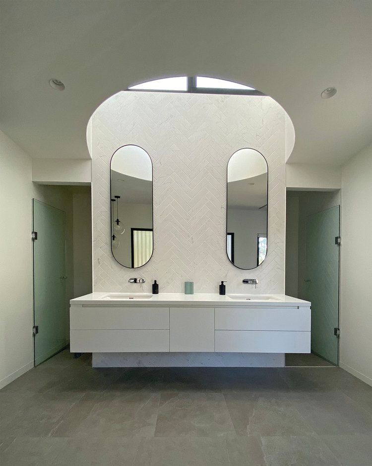 Modern double vanity bathroom with oval mirrors, white cabinets, and green stall doors — KM Custom Homes In Mount Eliza, VIC