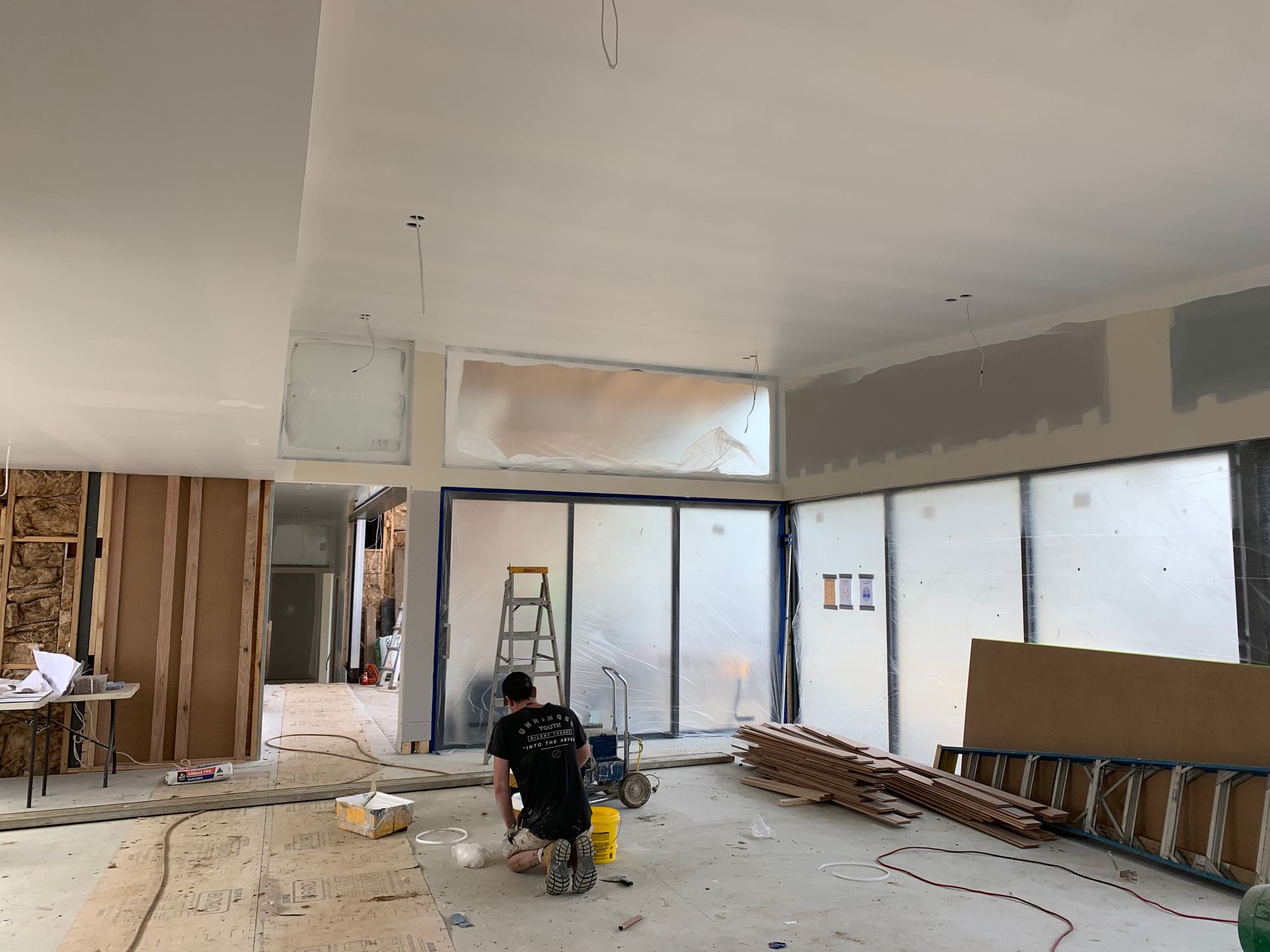 A Man Is Kneeling On The Floor In A Room Under Construction — KM Custom Homes In Mount Eliza, VIC